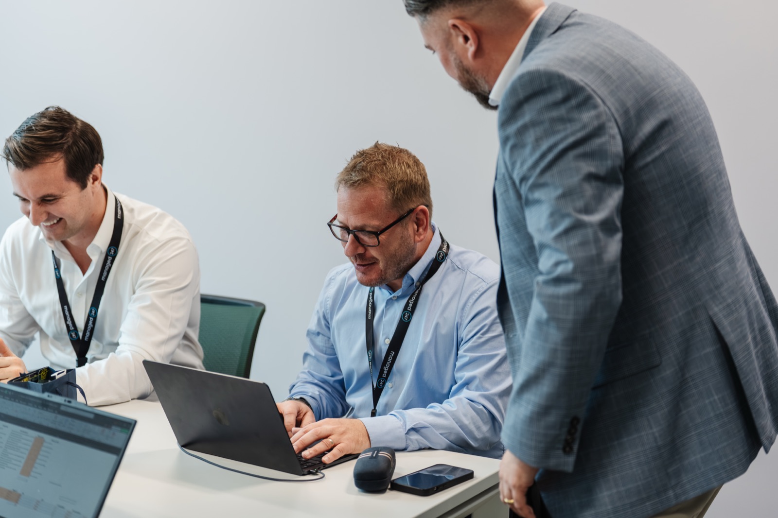 Three colleagues working together over laptops in a modern office