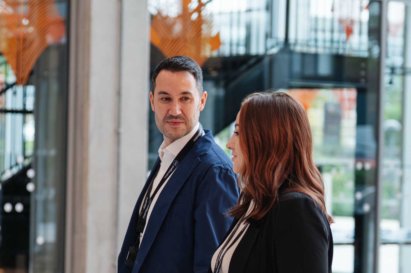 Two professionals in conversation in a bright office atrium