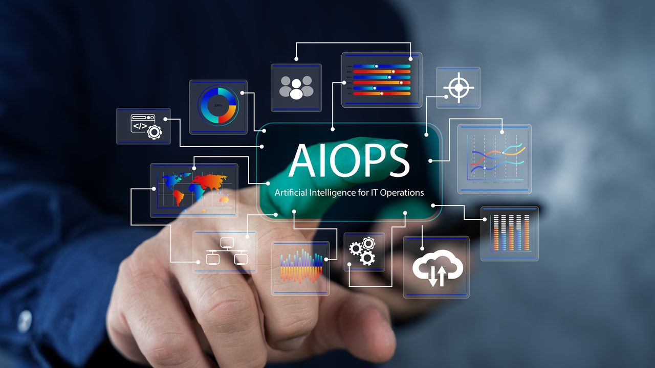 A hand reaching towards a digital AIOps display, surrounded by connected icons for analytics, networks, cloud and automation